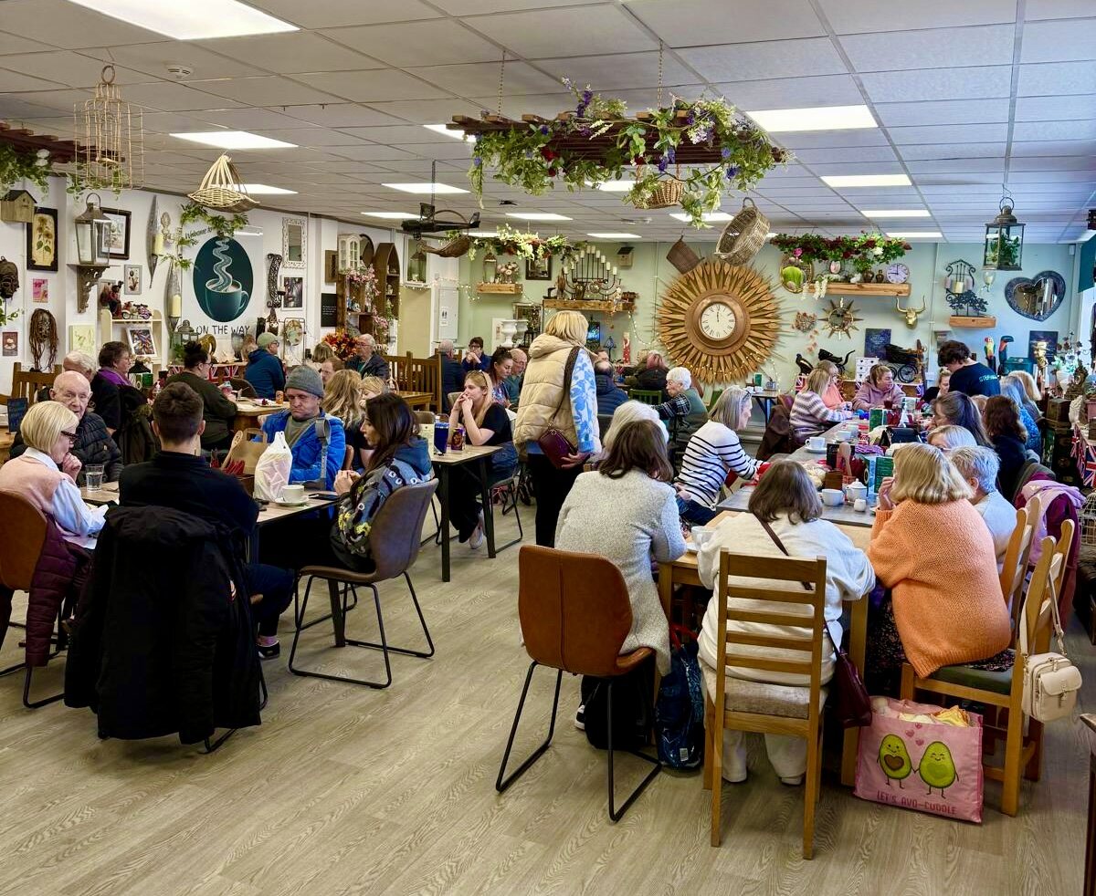 Customers enjoying a busy community gathering inside On the Way Coffee Shop
